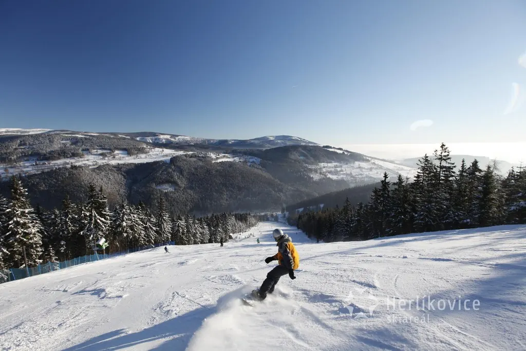 Snowboardista na sjezdovce v Herlíkovicích s výhledem na krkonošská údolí